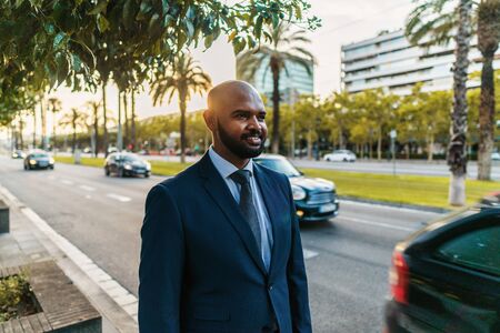 Indian businessman wearing blue suit standing near office or hotel.の写真素材
