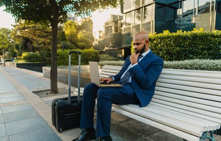 Indian businessman holding laptop notebook wearing blue suit near officeの写真素材