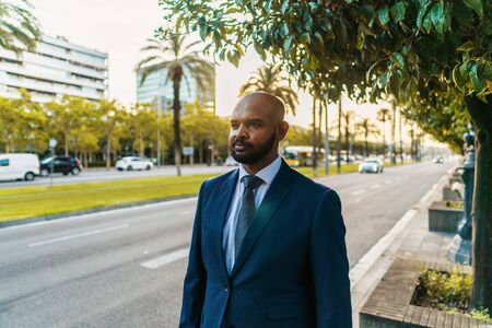 Indian businessman wearing blue suit standing near office or hotel.の写真素材