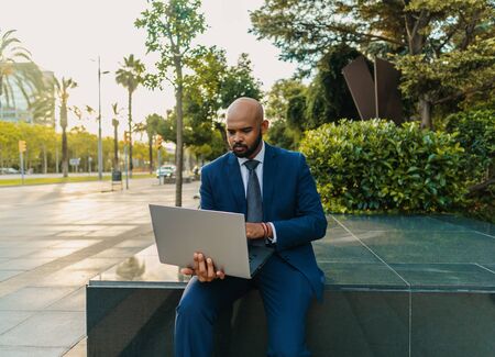 Indian businessman holding laptop notebook wearing blue suit near officeの写真素材