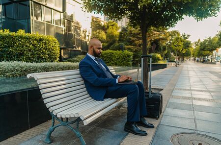Indian businessman holding laptop notebook wearing blue suit near officeの写真素材