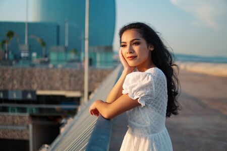 Beautiful girl in the white dress along the sea promenade.の写真素材