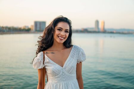 Beautiful girl in the white dress along the sea promenade.の写真素材
