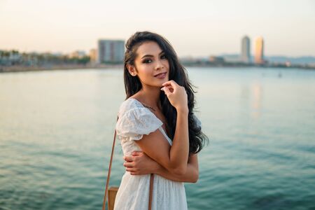 Beautiful girl in the white dress along the sea promenade.の写真素材