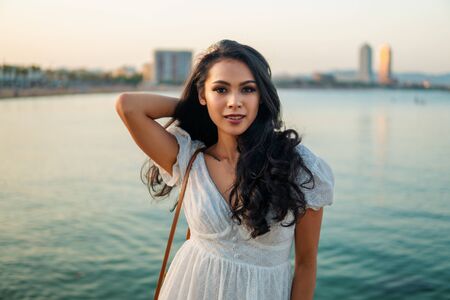 Beautiful girl in the white dress along the sea promenade.の写真素材