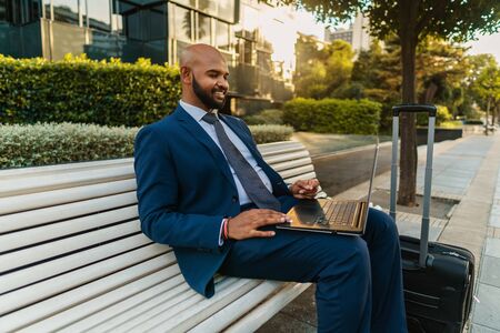 Indian businessman holding laptop notebook wearing blue suit near officeの写真素材