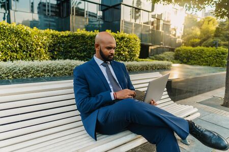 Indian businessman holding laptop notebook wearing blue suit near officeの写真素材