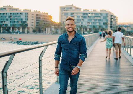 A young handsome man on the bridge near beautiful beach.の写真素材