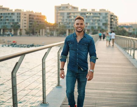 A young handsome man on the bridge near beautiful beach.の写真素材