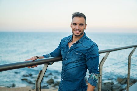 A young handsome man on the bridge near beautiful beach.の写真素材