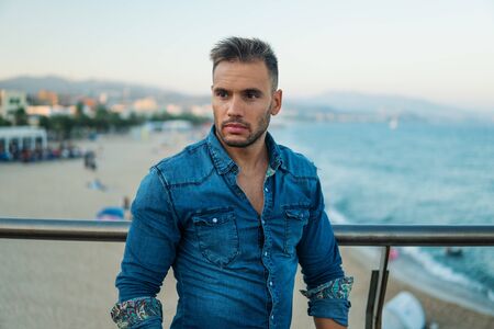 A young handsome man on the bridge near beautiful beach.の写真素材