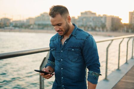 A young handsome man on the bridge near beautiful beach.の写真素材