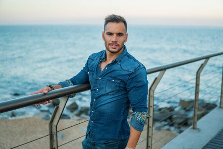 A young handsome man on the bridge near beautiful beach.の写真素材