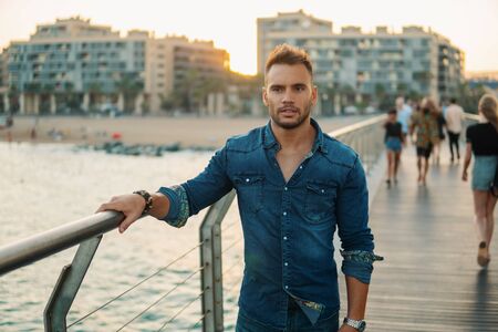 A young handsome man on the bridge near beautiful beach.の写真素材