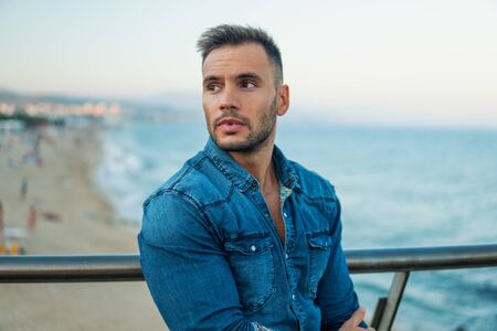 A young handsome man on the bridge near beautiful beach.の写真素材