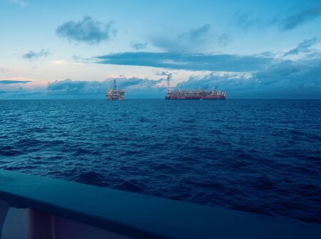 FPSO tanker vessel near Oil Rig platform. Offshore oil and gas industry. Flare is burning with smoke. View from supply vesselの写真素材