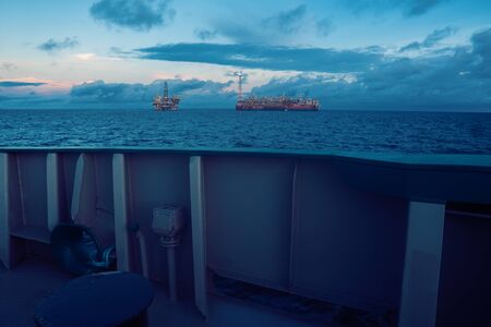 FPSO tanker vessel near Oil Rig platform. Offshore oil and gas industry. Flare is burning with smoke. View from supply vesselの写真素材