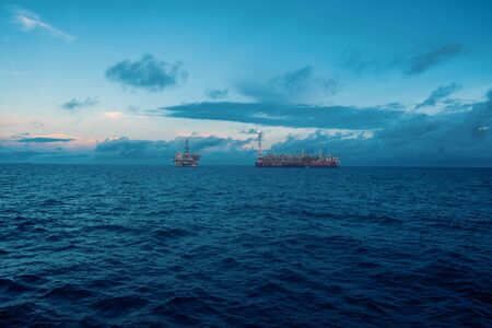FPSO tanker vessel near Oil Rig platform. Offshore oil and gas industry. Flare is burning with smoke. View from supply vesselの写真素材