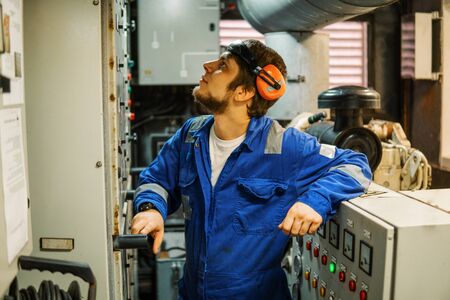 Marine engineer inspecting ship's engine or generators in engine control room ECR. Seamen's work.の写真素材