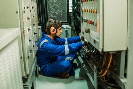 Marine engineer inspecting ship's engine or generators in engine control room ECR. Seamen's work.の写真素材