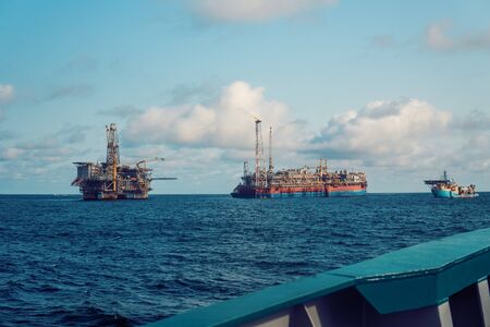 FPSO tanker vessel near Oil Rig platform. Offshore oil and gas industry. Flare is burning with smoke. View from supply vesselの写真素材