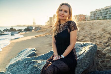 Young woman walking at beautiful ocean beach on sunsetの写真素材