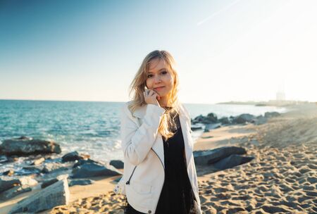 Young woman walking at beautiful ocean beach on sunsetの写真素材