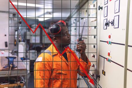 Concept of falling market in marine industry with downward graphics. Marine engineer officer working in engine roomの写真素材