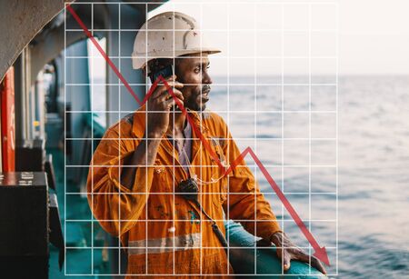 Concept of falling market in marine industry with downward graphics. Bosun or AB seaman on deck of vessel or shipの写真素材