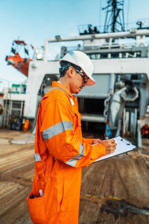 Filipino deck Officer on deck of offshore vessel or ship fills checklist. Paperwork at seaの写真素材