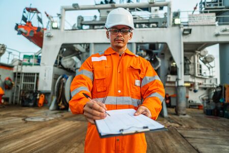 Filipino deck Officer on deck of offshore vessel or ship fills checklist. Paperwork at sea