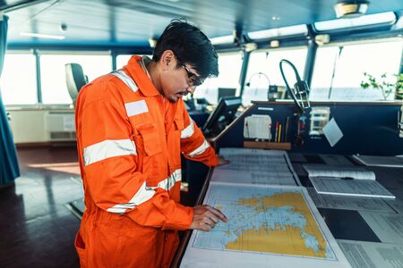 Filipino deck Officer on bridge of vessel or ship. He is plotting position on chartの写真素材
