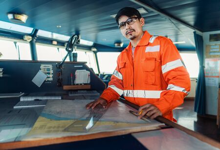 Filipino deck Officer on bridge of vessel or ship. He is plotting position on chartの写真素材