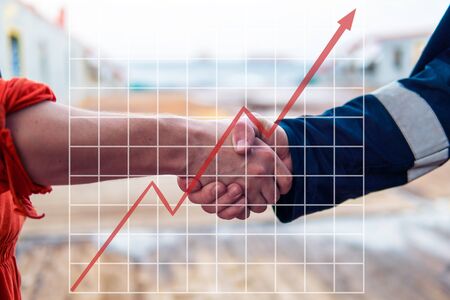 Concept of growth up in marine industry with rising graphics. marine contractor businessman handshaking with workerの写真素材
