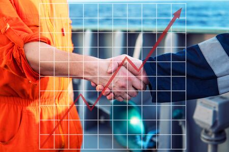 Concept of growth up in marine industry with rising graphics. marine contractor businessman handshaking with workerの写真素材