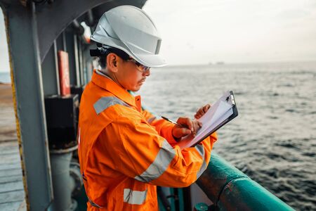 Filipino deck Officer on deck of offshore vessel or ship fills checklist. Paperwork at seaの写真素材