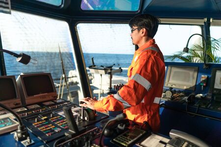 Filipino deck Officer on bridge of vessel or ship. He is speaking on GMDSS VHF radioの写真素材
