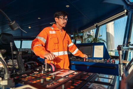 Filipino deck Officer on bridge of vessel or ship. He is speaking on GMDSS VHF radioの写真素材