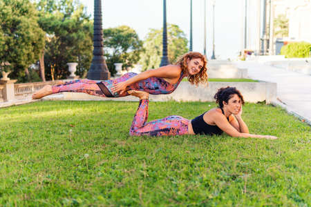 Two beautiful women doing acroyoga in the garden or parkの写真素材
