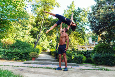 Beautiful man and woman doing acroyoga in the garden or parkの写真素材