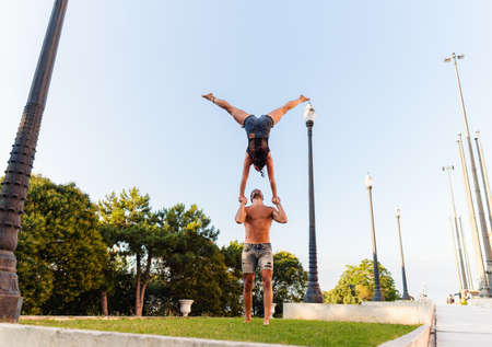 Beautiful man and woman doing acroyoga in the city park lawnの写真素材