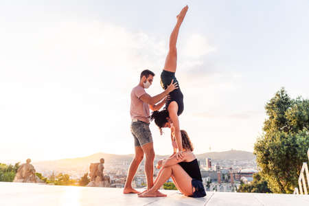 Beautiful man and two women doing acroyoga in the cityの写真素材