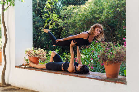 Two beautiful women doing acroyoga in the garden or parkの写真素材