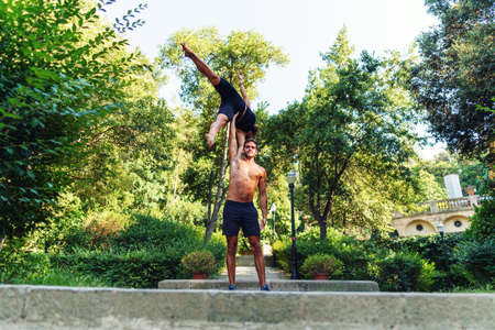 Beautiful man and woman doing acroyoga in the garden or parkの写真素材