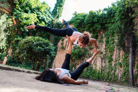Two beautiful women doing acroyoga in the garden or parkの写真素材