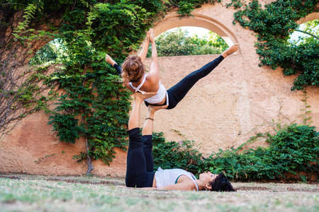 Two beautiful women doing acroyoga in the garden or parkの写真素材