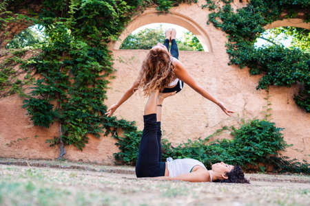 Two beautiful women doing acroyoga in the garden or park
