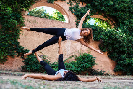 Two beautiful women doing acroyoga in the garden or parkの写真素材