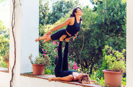 Two beautiful women doing acroyoga in the garden or parkの写真素材