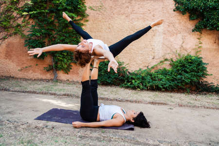 Two beautiful women doing acroyoga in the garden or parkの写真素材